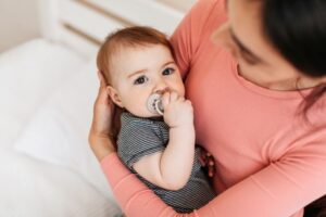 Baby using a pacifier while cradled in Mom's arms